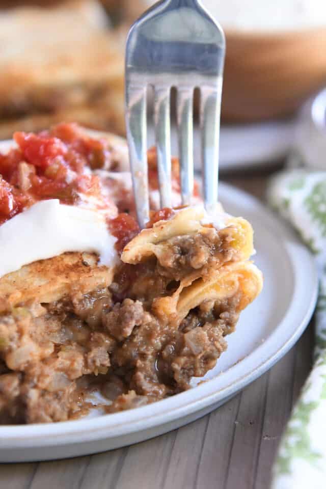 Fork piercing bite of two beef and bean wraps.