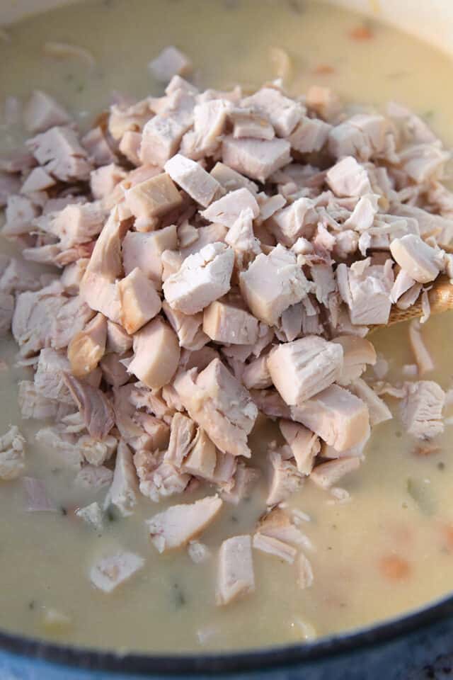 Cooked, cubed chicken in pot of soup.