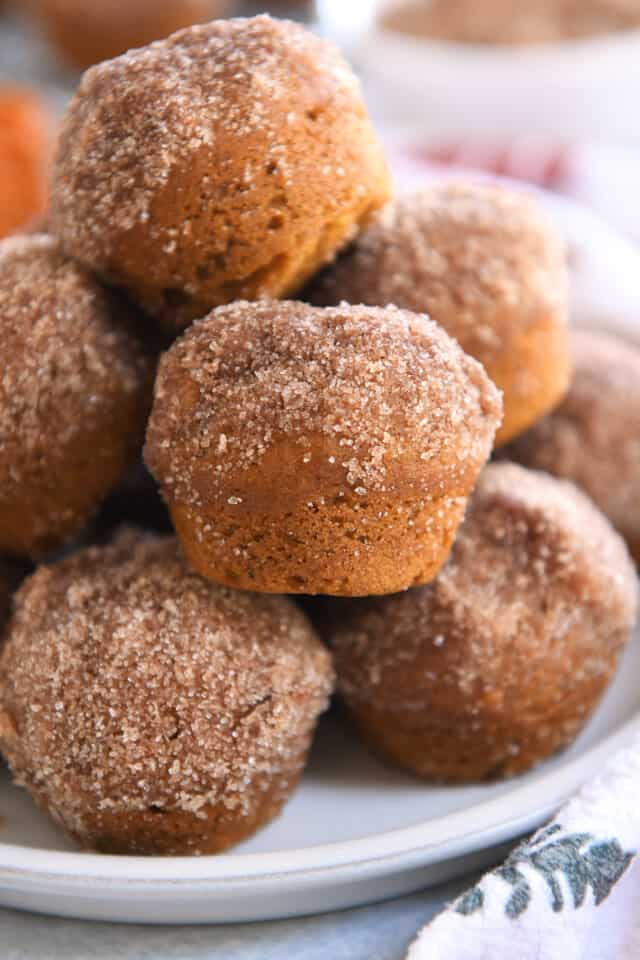 Several pumpkin mini muffins stacked on each other on plate.