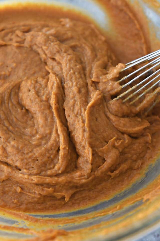 Whisking pumpkin muffin batter in glass bowl.
