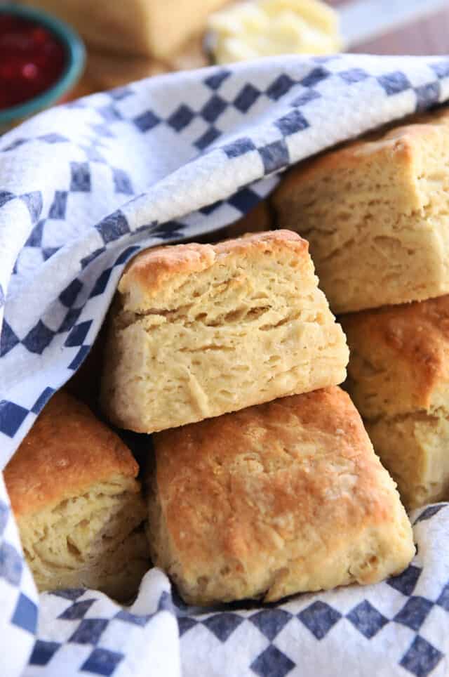 Baked biscuits in basket with blue and white towel.