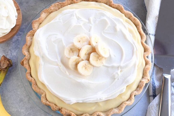 Top down view of banana cream pie topped with whipped cream and sliced bananas.