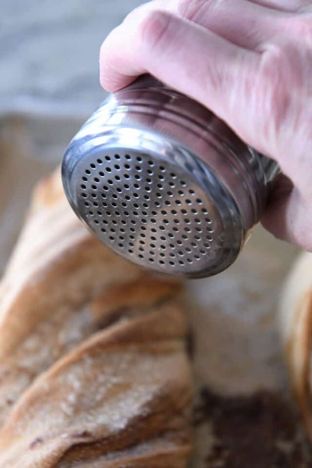 Sprinkling cinnamon sugar mixture on top of bread.