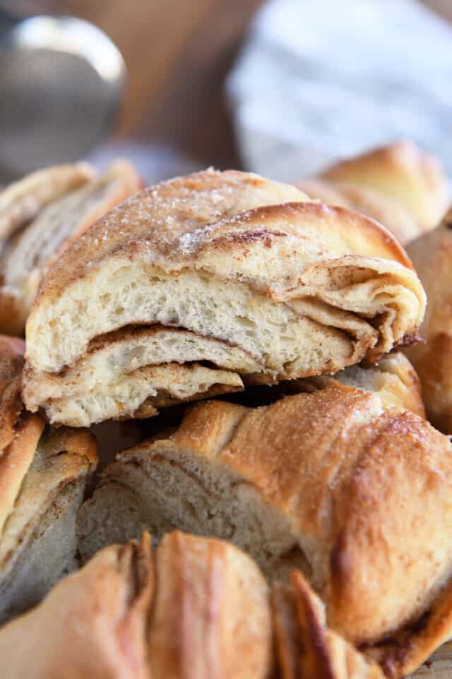Piece of cinnamon sugar twisted croissant bread on top of several other pieces of bread.