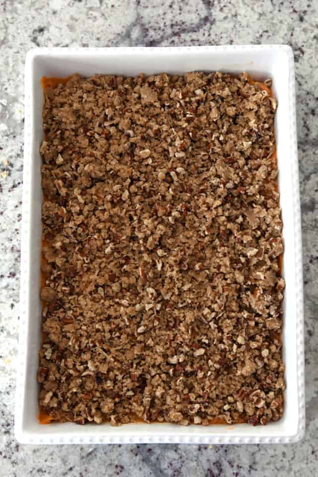 White baking dish with sweet potato filling and buttery pecan topping.
