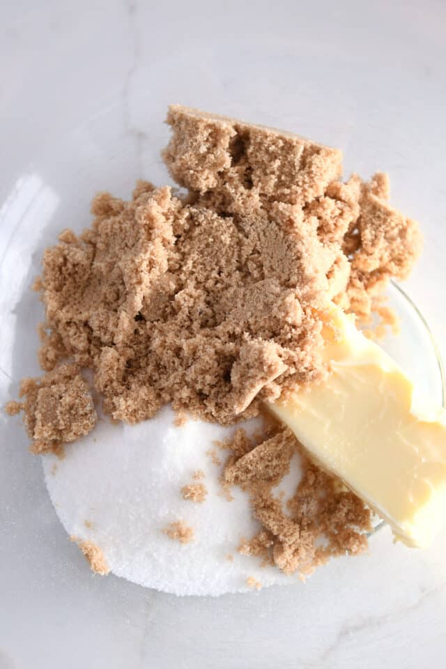 Glass bowl with brown sugar, granulated sugar and butter.