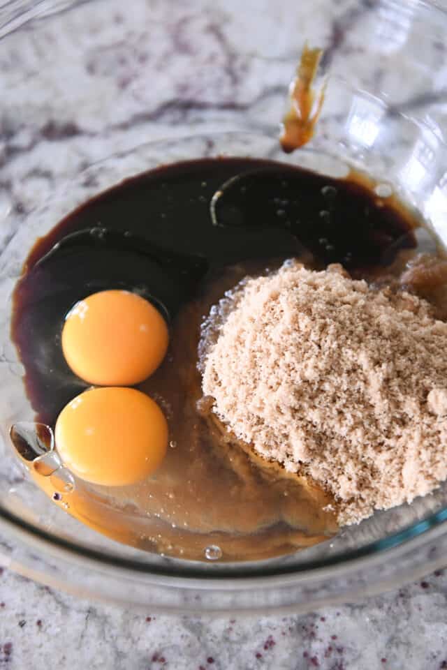 Glass bowl with eggs, brown sugar, molasses and oil.