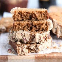 Four half pieces of gingerbread loaf stacked on white parchment paper.