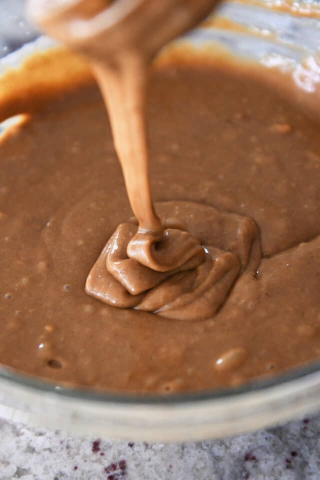 Gingerbread batter drizzling into bowl from whisk.