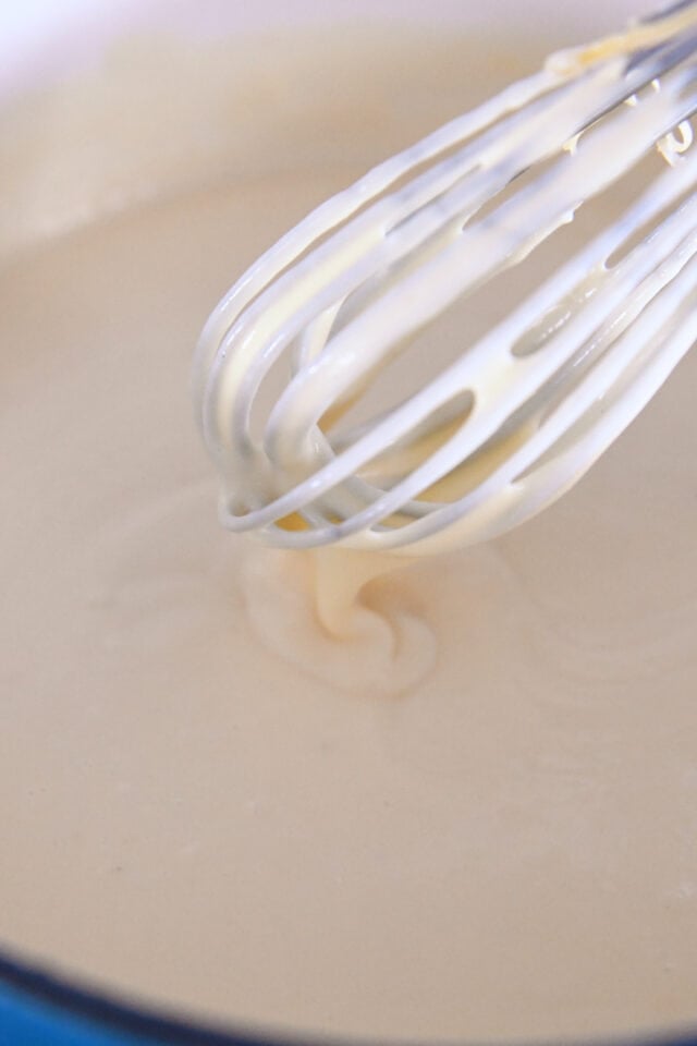 Whisk stirring cheese sauce for macaroni and cheese.
