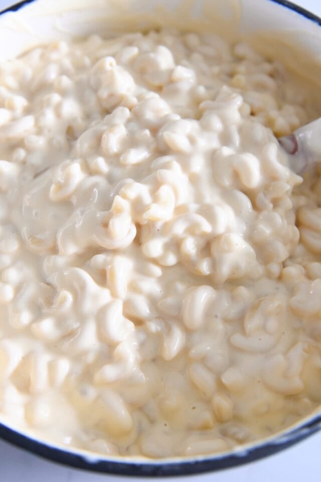 Macaroni noodles and cheese sauce mixed together in large pot.