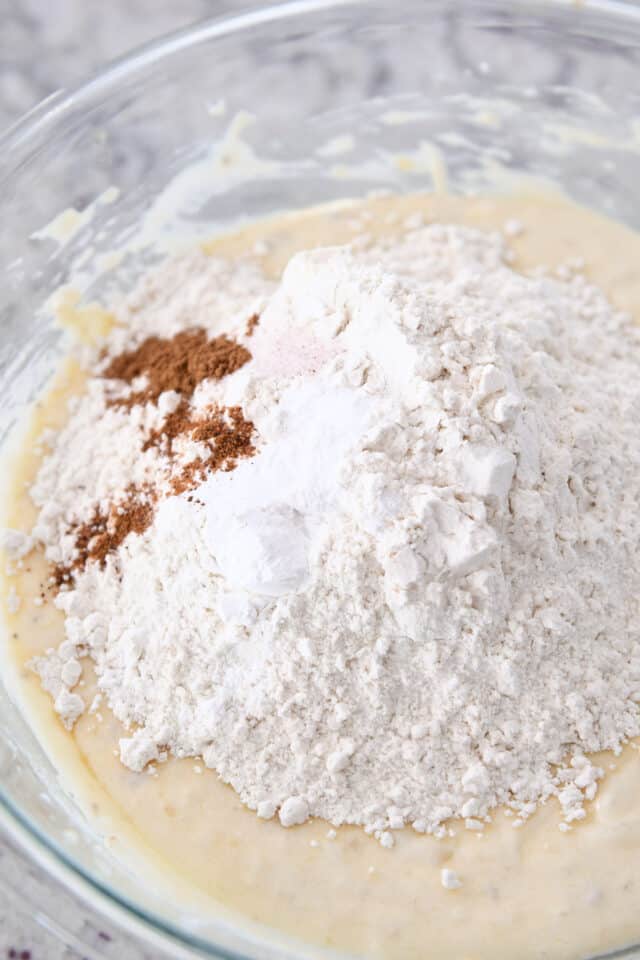 Flour, cinnamon, salt and baking powder in glass bowl with banana bread batter.