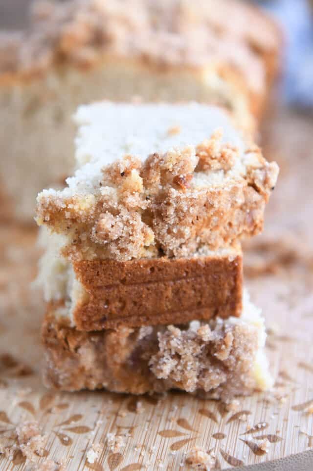 Three half slices of cream cheese banana bread stacked on wood cutting board.