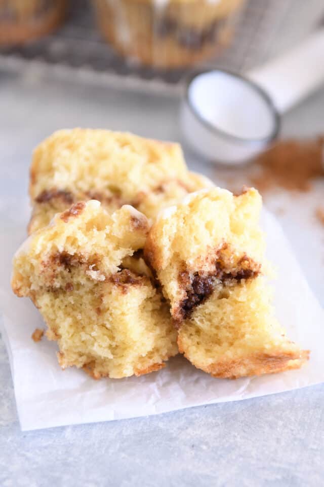 Cinnamon roll muffin in pieces on parchment paper.