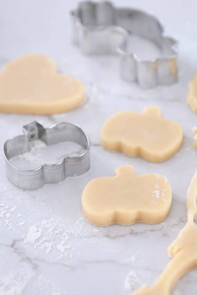 Unbaked pumpkin shaped sugar cookies on counter.