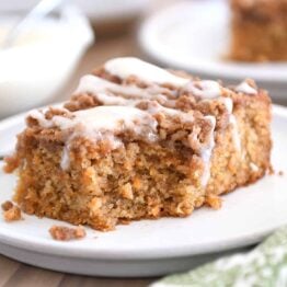 Bite taken out of carrot cake coffee cake on light gray plate.