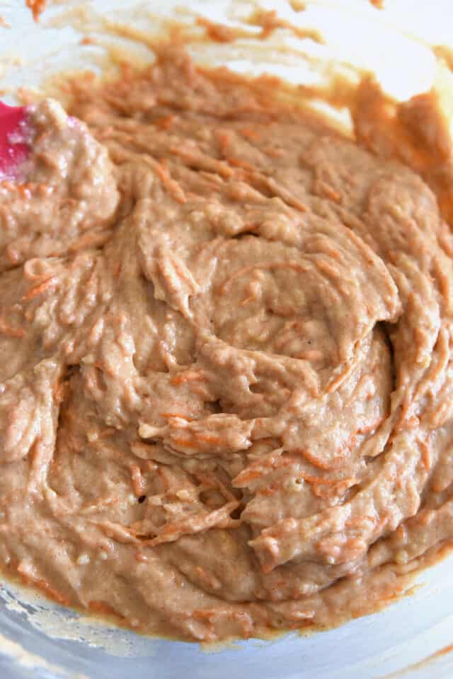 Mixed carrot cake batter in glass bowl.