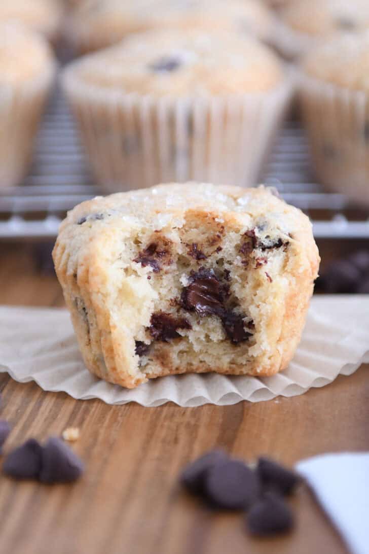 Bite taken out of chocolate chip muffin with melty chocolate chips in the middle.