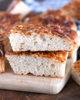 Two stacked pieces of fluffy Italian cheese bread on wood cutting board.