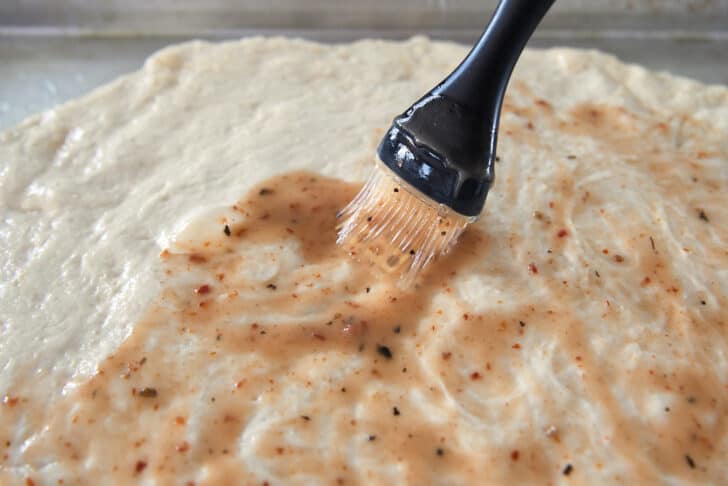 Brushing Italian salad dressing on dough.