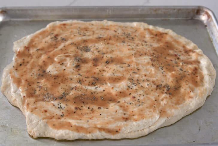 Herbs and salt sprinkled on top of dough on half sheet pan.