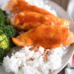 Plate with broccoli, rice and saucy chicken tenders.
