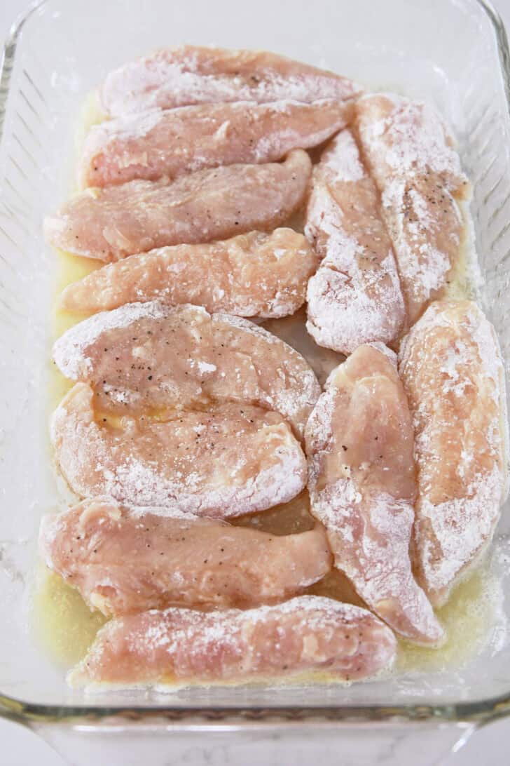 Chicken tenders tossed in flour and placed in buttered glass baking dish.