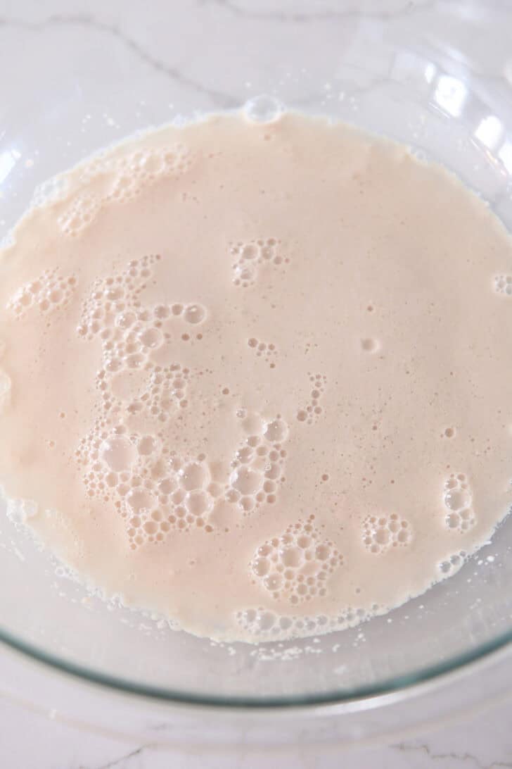 Foamy yeast in water in glass bowl.