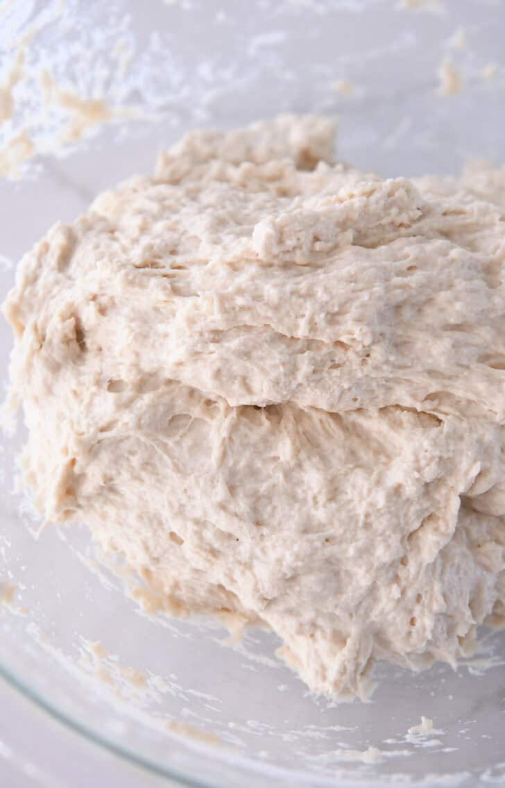 Shaggy bread dough mixed in glass bowl.