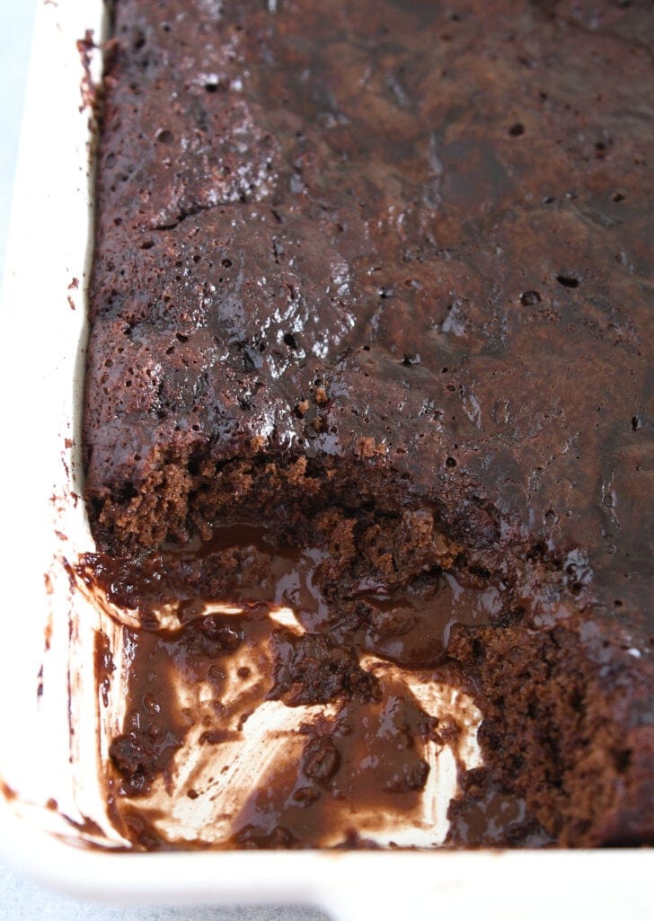 Top down view of hot fudge pudding cake in white 9X13-inch dish with portion removed.
