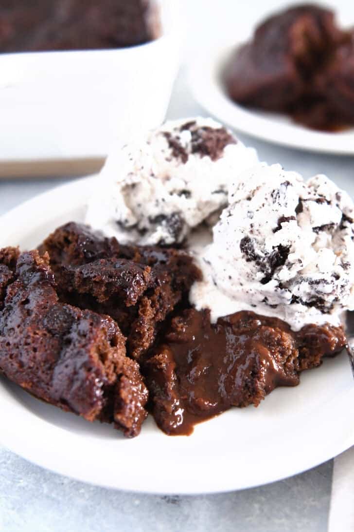 Hot fudge pudding cake on white plate with ice cream.
