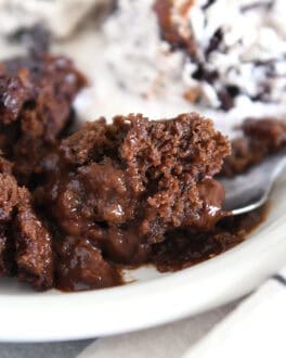 Spoonful of decadent hot fudge pudding cake on white plate.