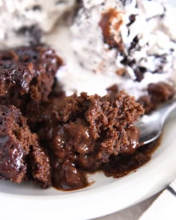 Spoonful of ooey gooey hot fudge pudding cake on white plate.