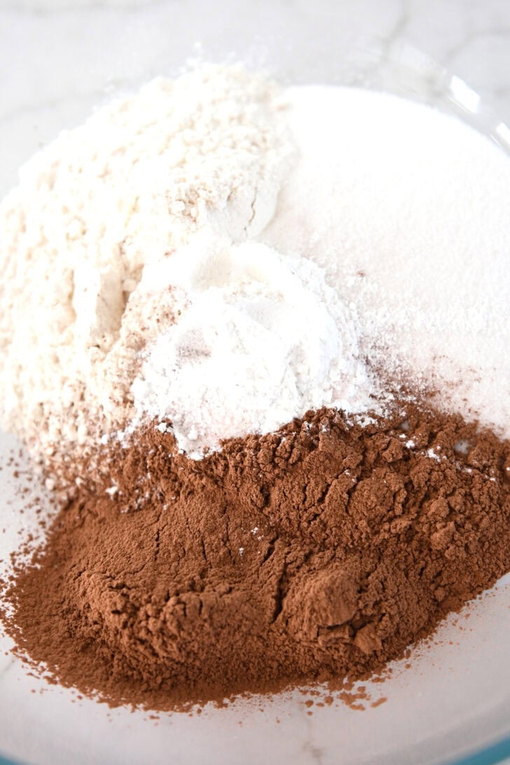 Cocoa powder, sugar, flour and baking powder in glass bowl.