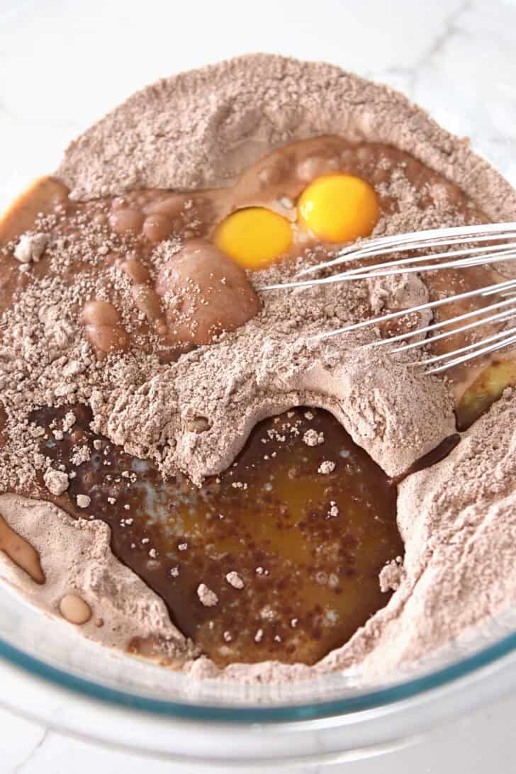 Eggs and butter added to chocolate cake mix in glass bowl.