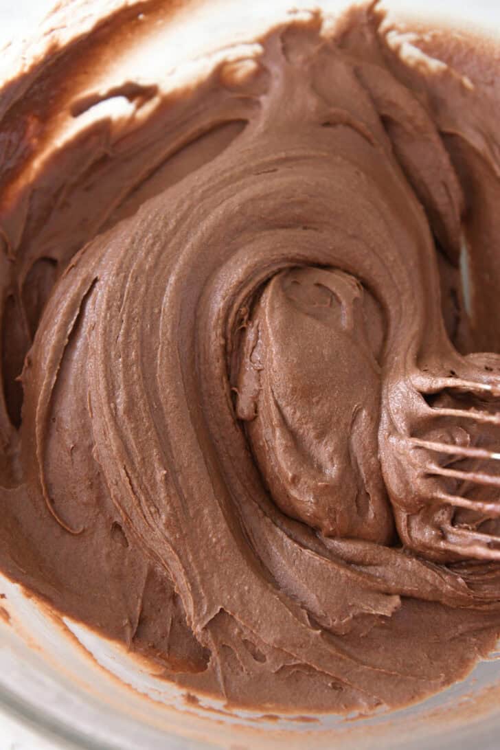 Whisking chocolate cake batter in glass bowl.