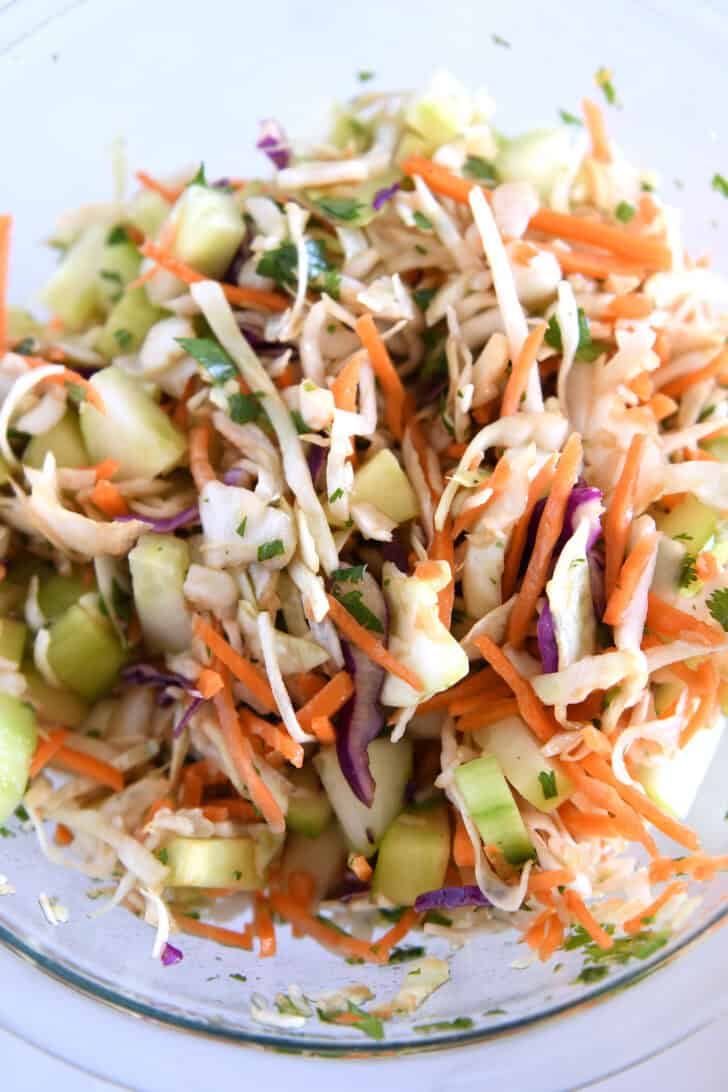 Glass bowl with cabbage, lime juice, cilantro.