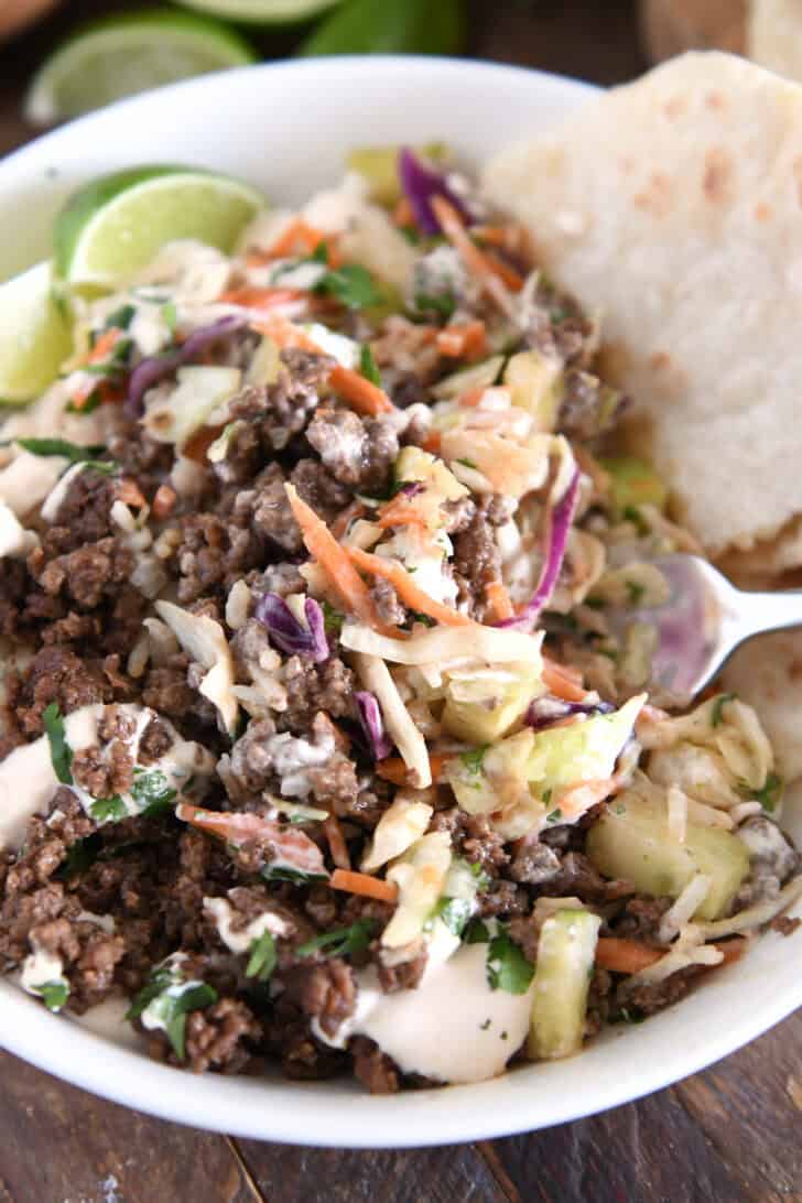 White bowl with tossed together rice, slaw, sauce and Korean beef.