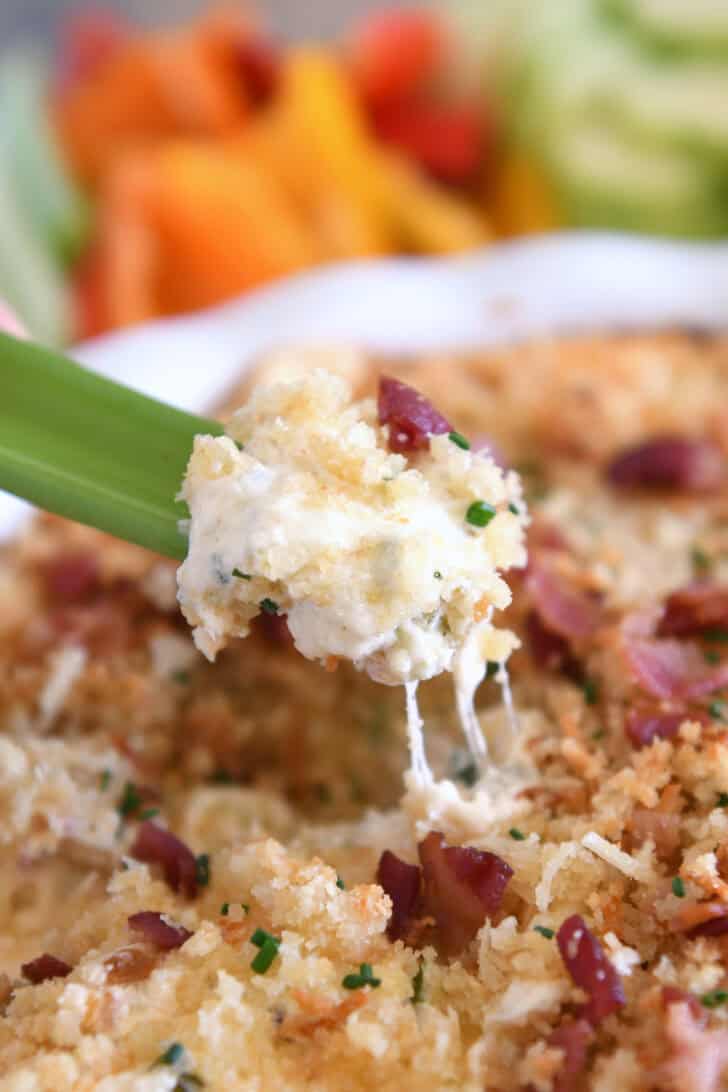 Creamy cheesy bacon dip on piece of celery.