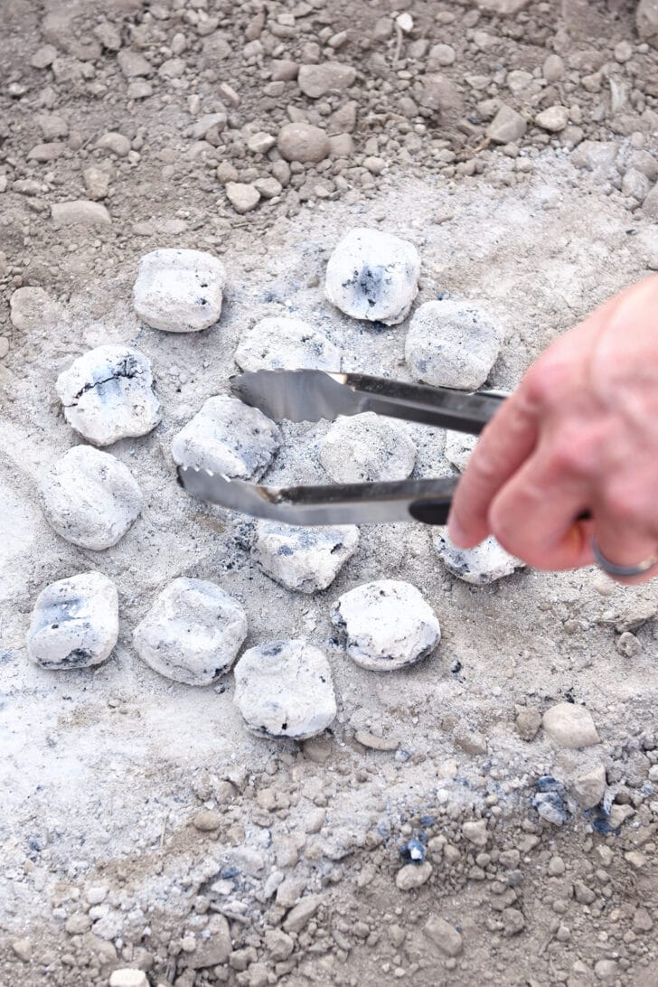 Placing hot coals in dirt for Dutch oven.
