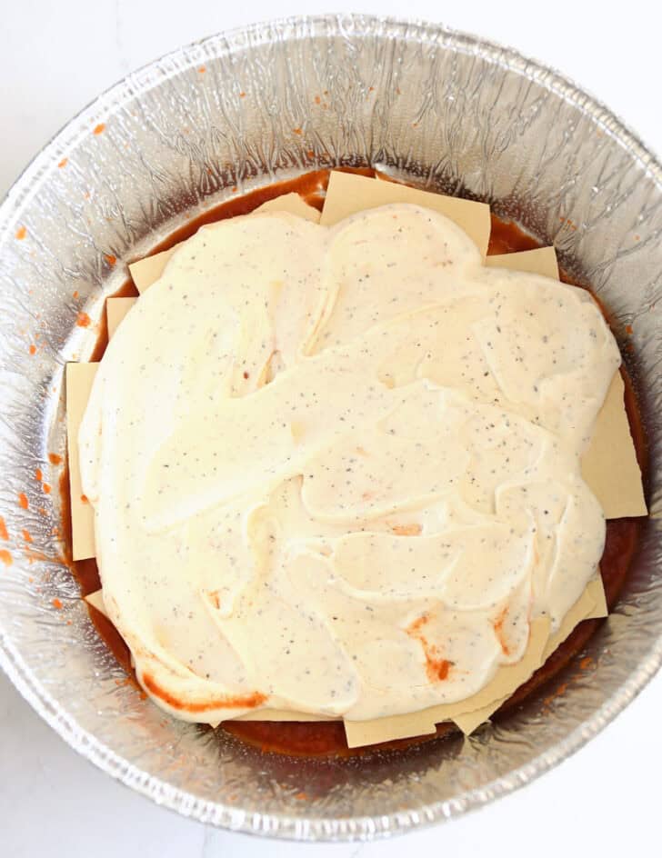 Top down view of creamy mixture over noodles in Dutch oven liner.