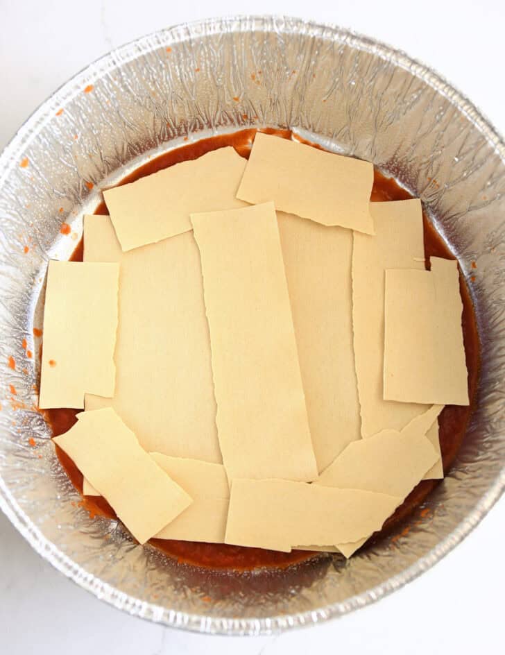 Top down view of broken lasagna noodles in Dutch oven liner.