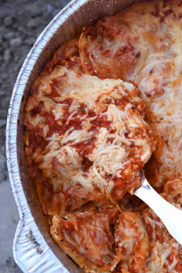 Serving spoon scooping portion of Dutch oven lasagna.