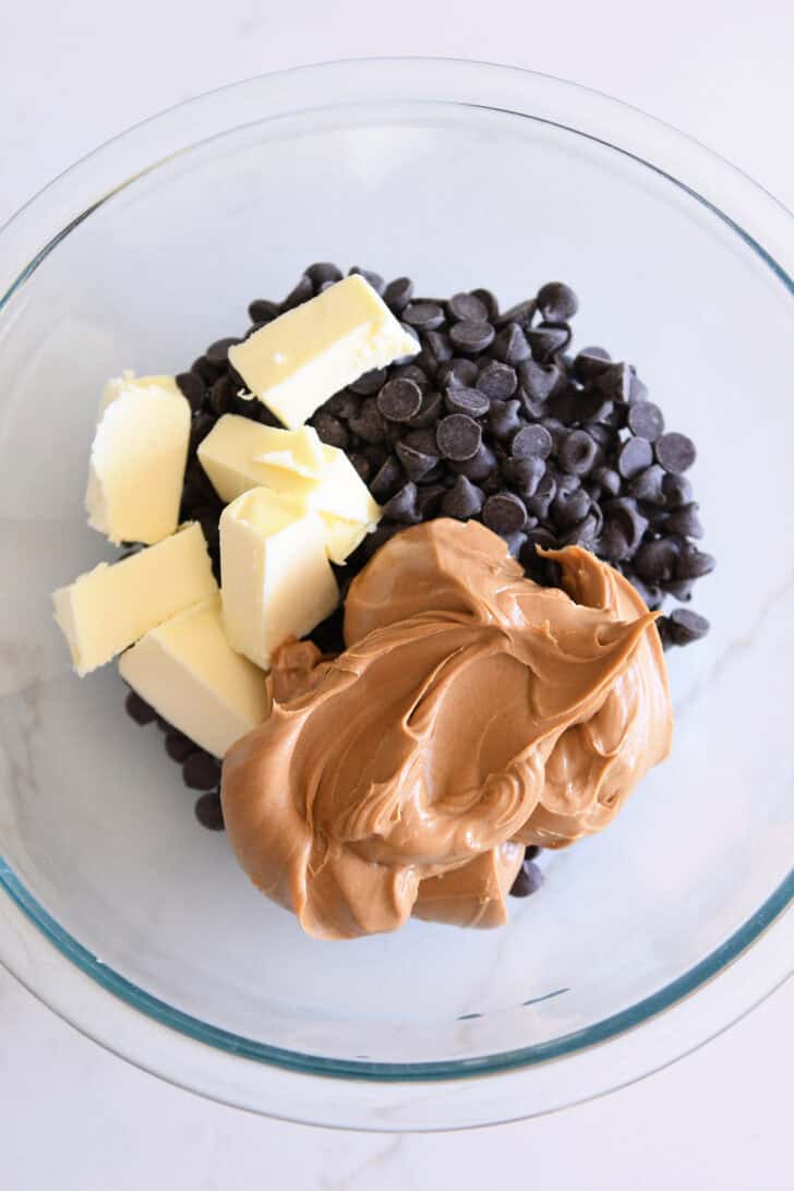 Butter, peanut butter, and chocolate chips in glass bowl.