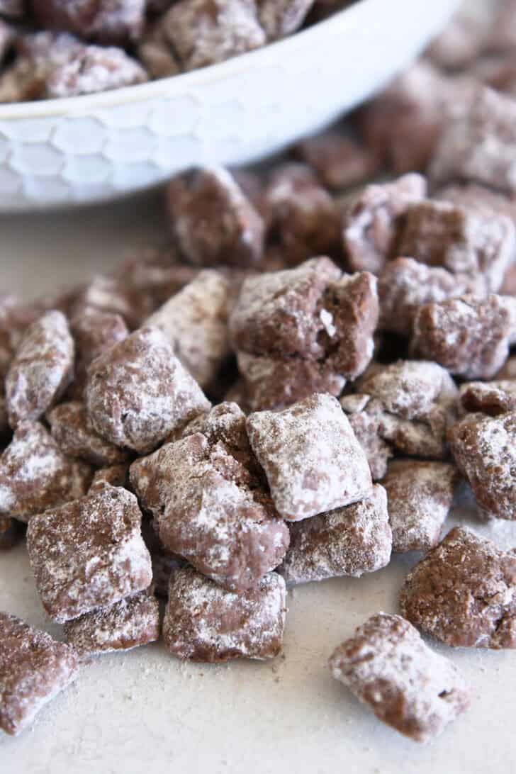Several pieces of peanut butter and chocolate puppy chow coated with powdered sugar.