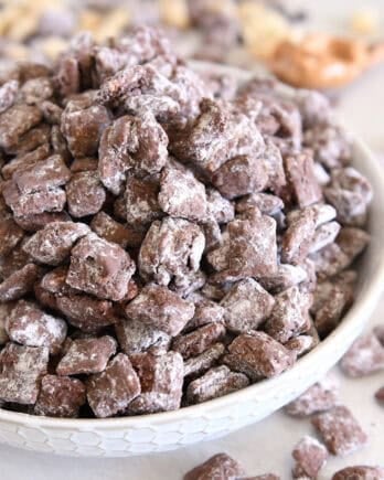 Pile of peanut butter and chocolate puppy chow in white bowl.