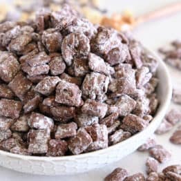 White bowl filled with towering pile of peanut butter and chocolate coated chex cereal.