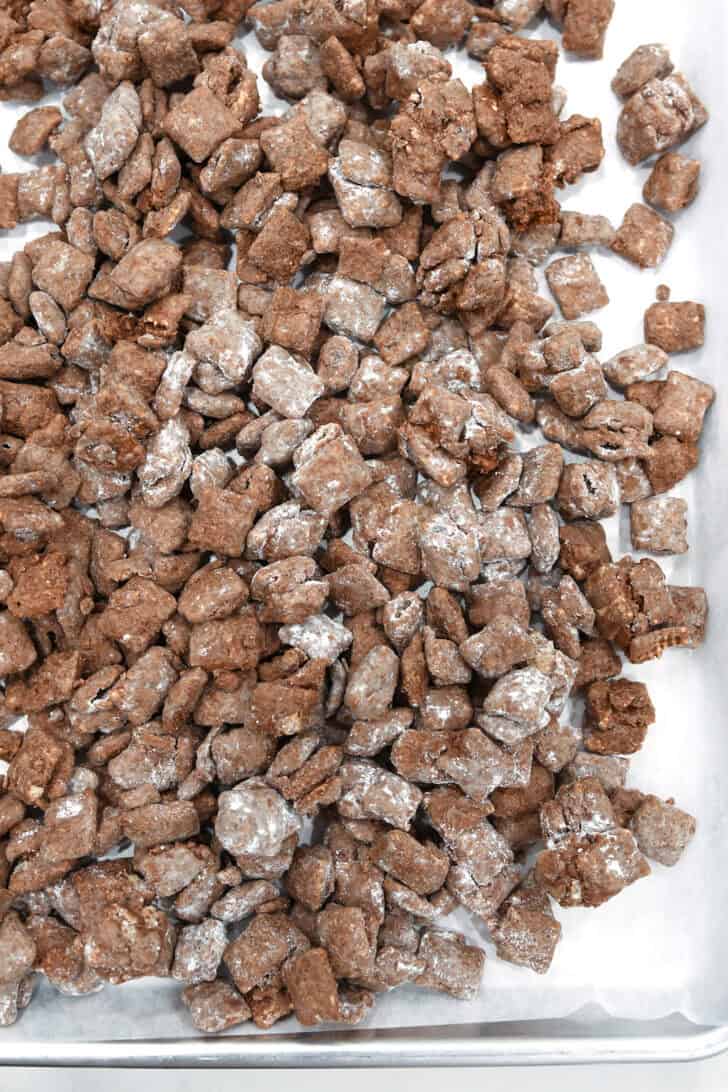 Puppy chow on parchment lined baking sheet.