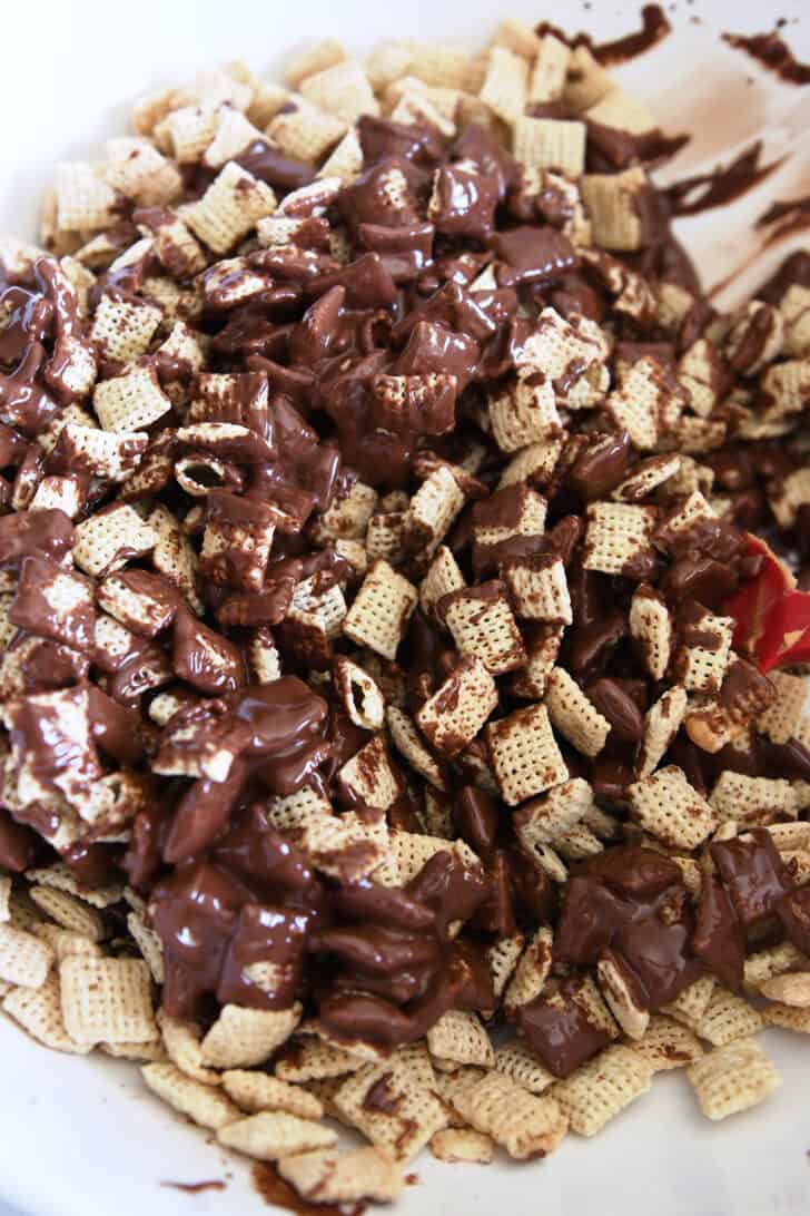 Stirring rice chex cereal with peanut butter and chocolate.