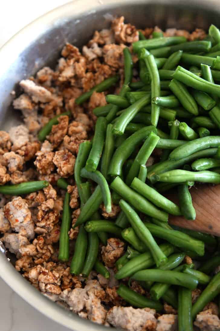 Top down view of ground turkey and green beans in skillet.